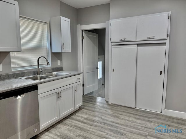 kitchen featuring sink, white cabinetry, stainless steel dishwasher, and light wood-type flooring