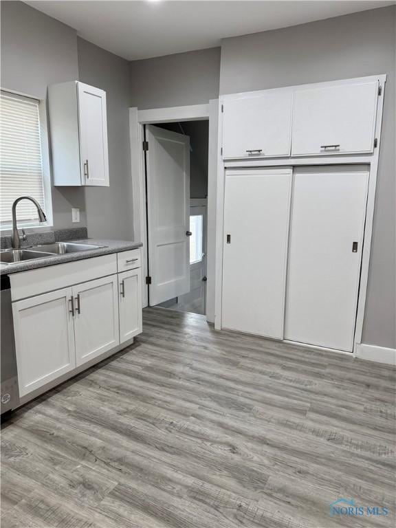 kitchen featuring a healthy amount of sunlight, sink, white cabinetry, and light hardwood / wood-style flooring