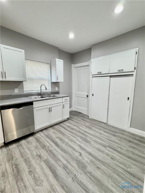 kitchen featuring white cabinetry, light hardwood / wood-style floors, stainless steel dishwasher, and sink