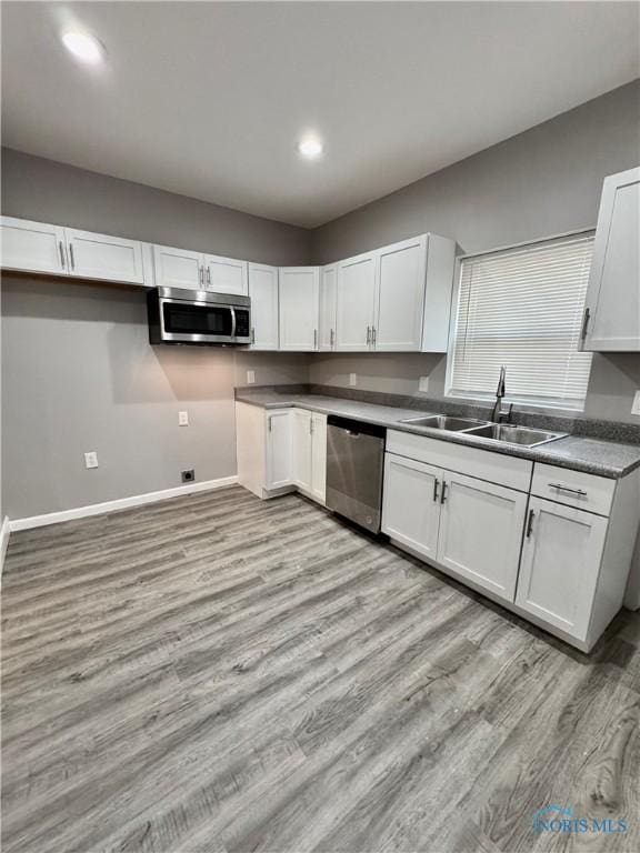 kitchen with light hardwood / wood-style floors, sink, white cabinets, and stainless steel appliances