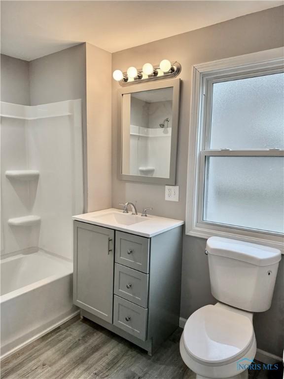 full bathroom with toilet, vanity, wood-type flooring, and shower / tub combination