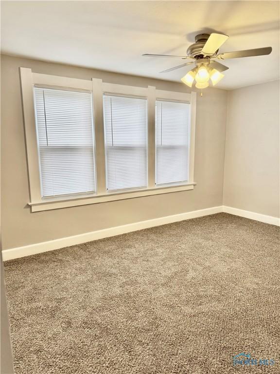 carpeted spare room featuring ceiling fan