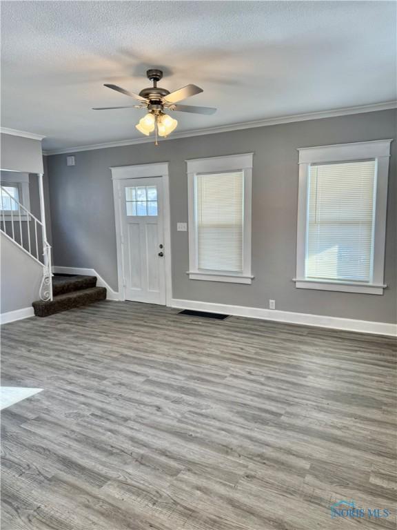 entrance foyer featuring ceiling fan, a textured ceiling, ornamental molding, and light hardwood / wood-style flooring