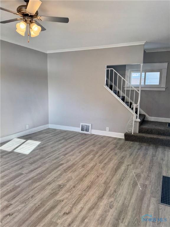 unfurnished living room with ceiling fan, ornamental molding, and hardwood / wood-style flooring