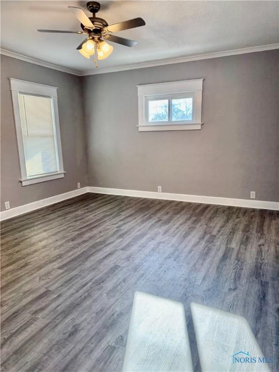 empty room with ceiling fan, dark hardwood / wood-style flooring, and crown molding