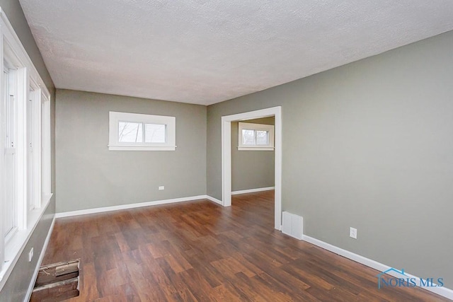 spare room with a textured ceiling and dark hardwood / wood-style flooring