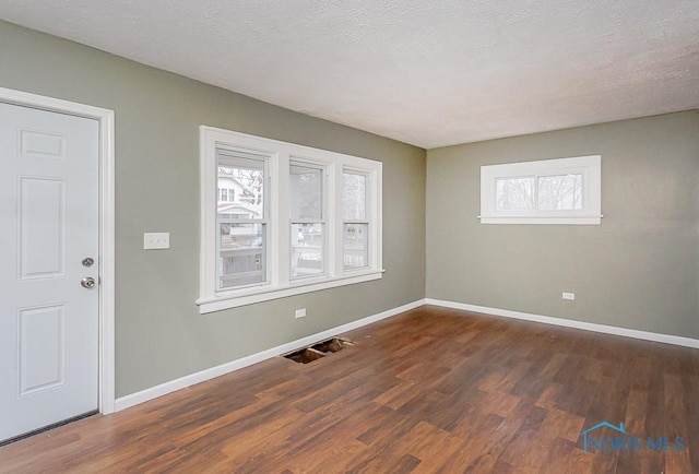 spare room featuring a textured ceiling and dark hardwood / wood-style flooring