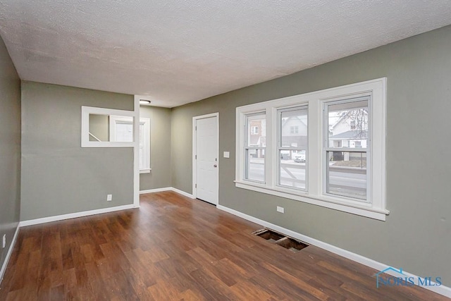 spare room featuring dark hardwood / wood-style flooring and a textured ceiling