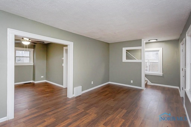 empty room featuring ceiling fan, dark hardwood / wood-style flooring, and a textured ceiling