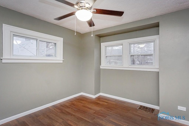 empty room featuring dark hardwood / wood-style floors, ceiling fan, and a textured ceiling