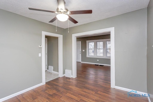 spare room featuring a textured ceiling, ceiling fan, and dark wood-type flooring