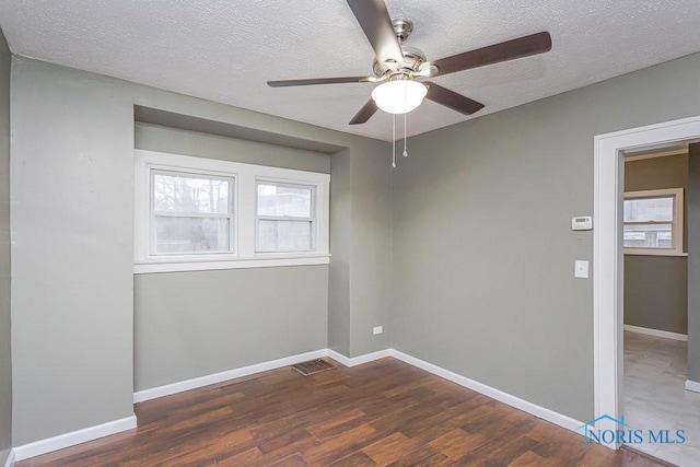 unfurnished room featuring dark hardwood / wood-style floors, ceiling fan, and a textured ceiling