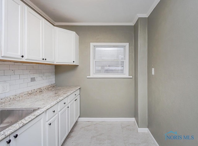 kitchen with light stone counters, white cabinetry, ornamental molding, and tasteful backsplash