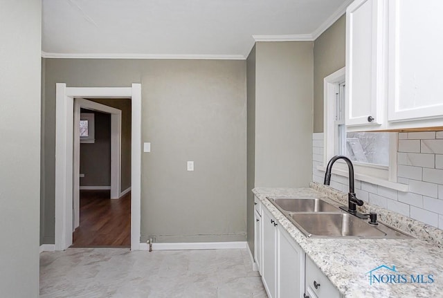 kitchen with white cabinets, backsplash, ornamental molding, and sink