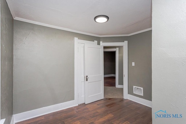 empty room with crown molding and dark wood-type flooring