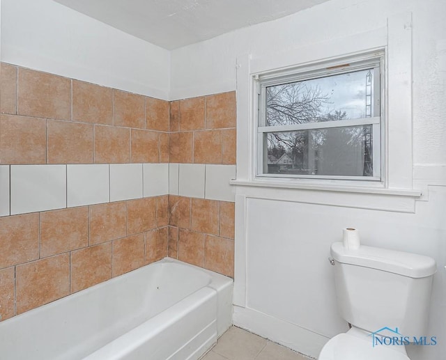 bathroom featuring tile patterned flooring, toilet, and a tub