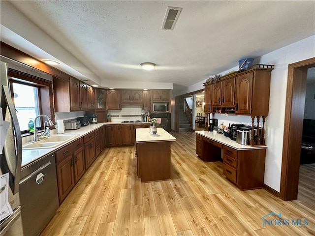 kitchen with appliances with stainless steel finishes, a center island, light hardwood / wood-style flooring, and sink