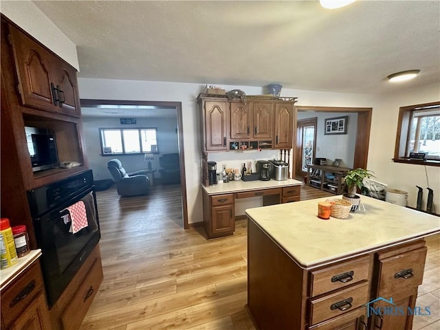 kitchen featuring black oven, a center island, and light wood-type flooring