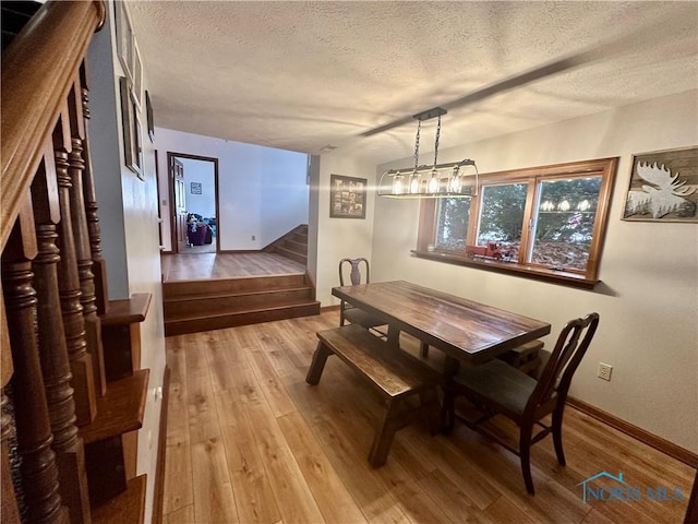 dining space featuring a textured ceiling and light hardwood / wood-style flooring