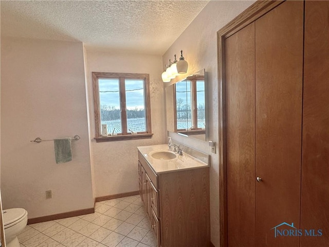 bathroom featuring vanity, a water view, a textured ceiling, and toilet