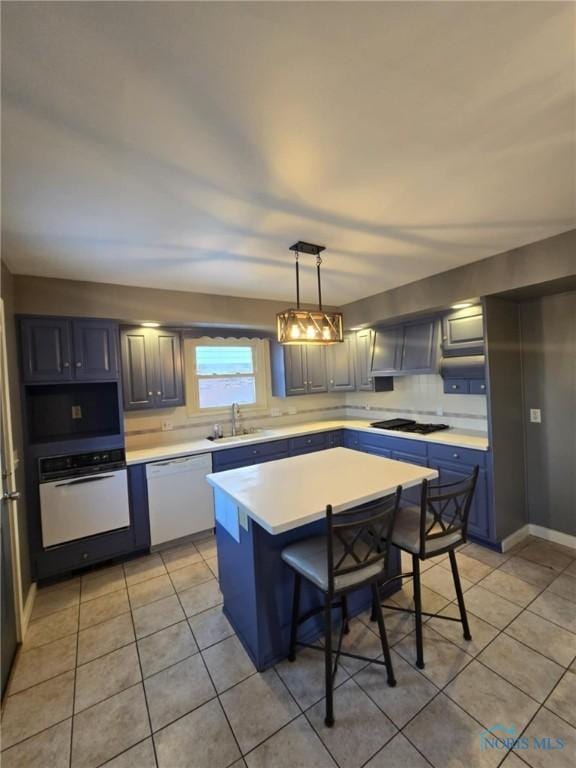 kitchen with pendant lighting, sink, a kitchen breakfast bar, a center island, and white appliances