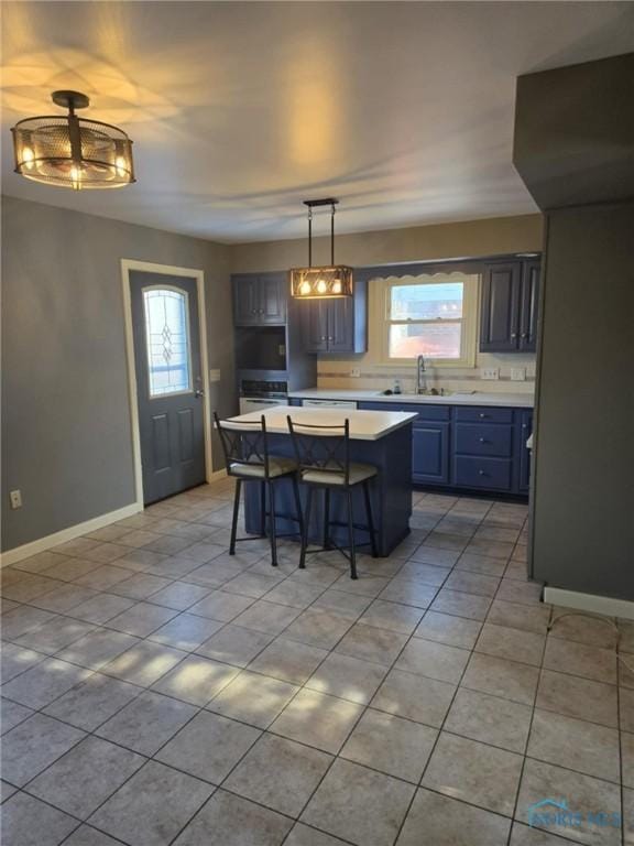 kitchen featuring light tile patterned flooring, a kitchen island, sink, a breakfast bar area, and hanging light fixtures