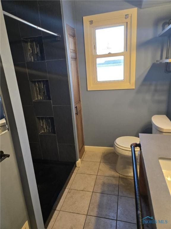 bathroom with a shower, vanity, tile patterned floors, and toilet