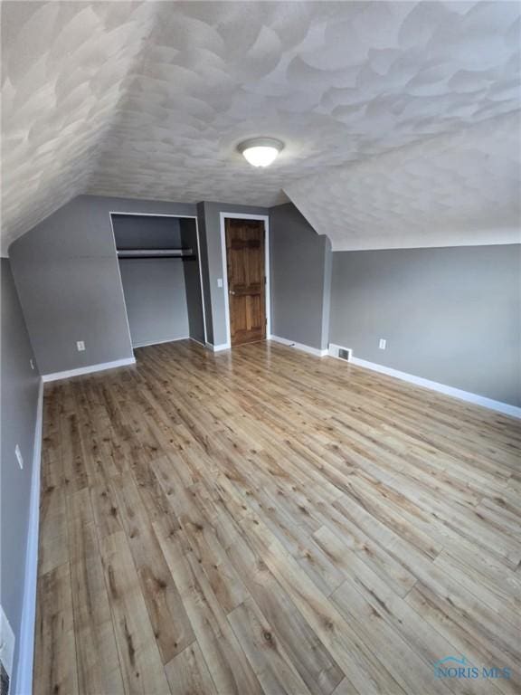 additional living space with lofted ceiling and light hardwood / wood-style floors