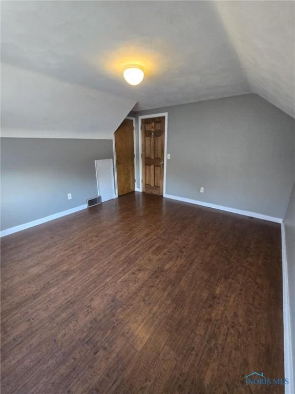 additional living space featuring lofted ceiling and dark hardwood / wood-style floors