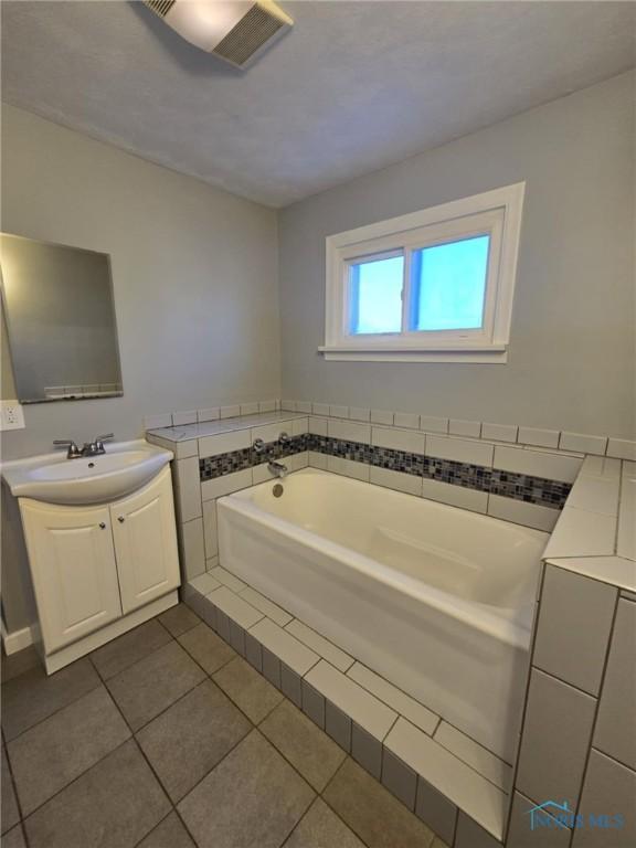 bathroom with vanity, a bath, and tile patterned floors