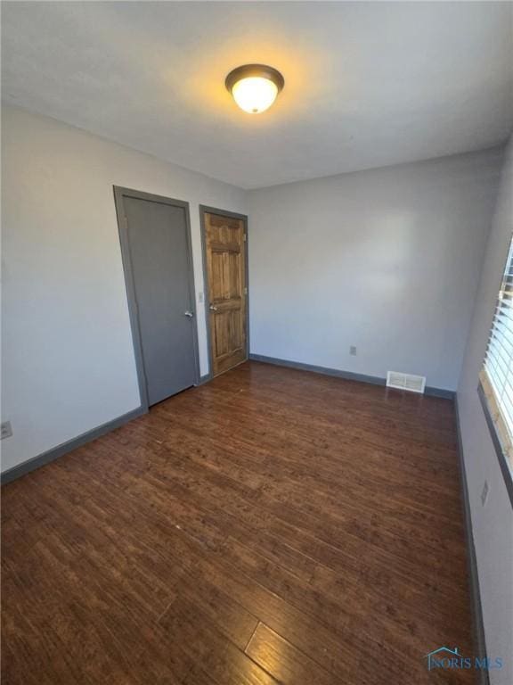 spare room with dark wood-type flooring