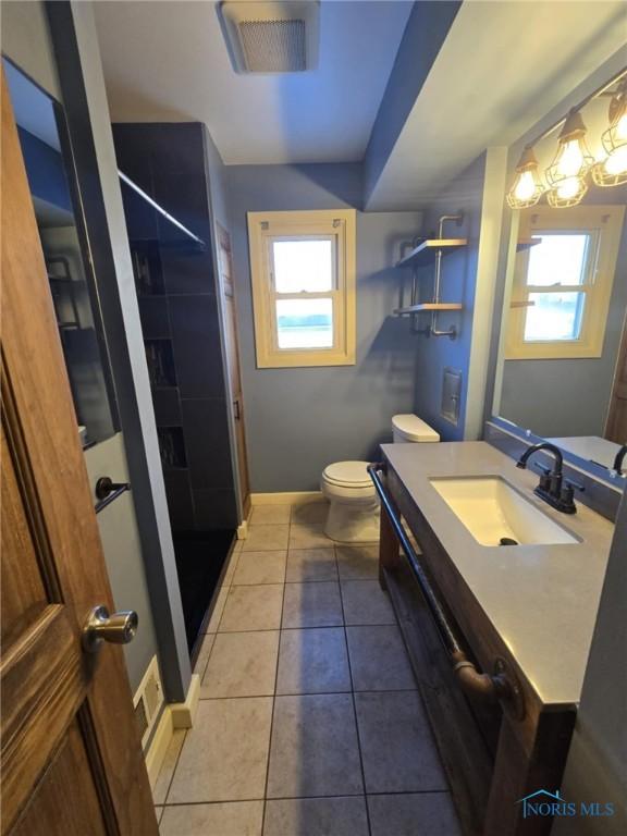 bathroom featuring vanity, tile patterned floors, toilet, and walk in shower