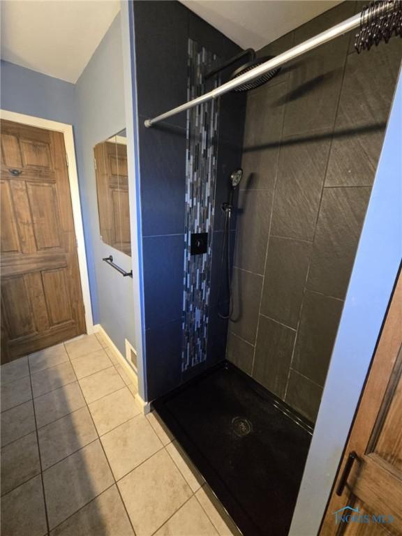 bathroom with tile patterned floors and a tile shower