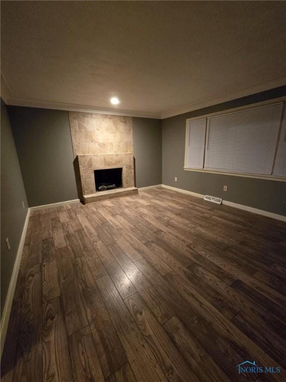 unfurnished living room featuring dark wood-type flooring, a fireplace, and crown molding