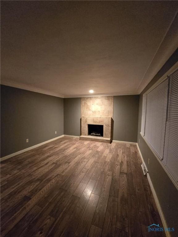 unfurnished living room featuring crown molding, a large fireplace, and dark hardwood / wood-style flooring