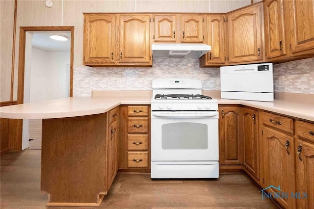 kitchen with light wood-type flooring, kitchen peninsula, backsplash, and white gas stove