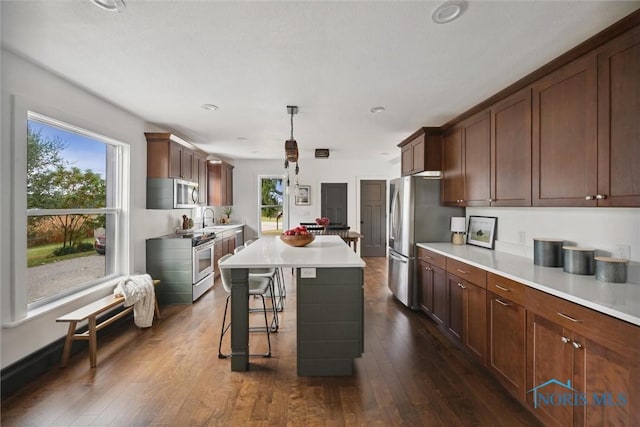 kitchen featuring sink, a center island, a healthy amount of sunlight, decorative light fixtures, and appliances with stainless steel finishes