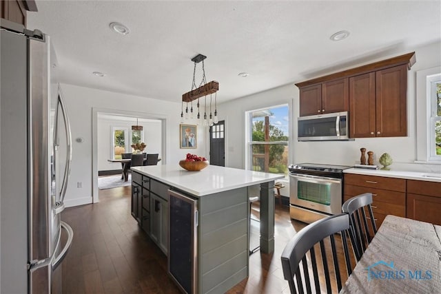 kitchen featuring stainless steel appliances, a kitchen island, pendant lighting, dark hardwood / wood-style floors, and wine cooler