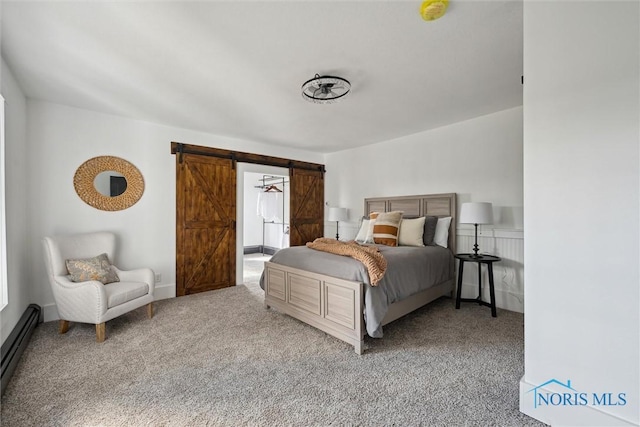 carpeted bedroom with a barn door and a baseboard heating unit