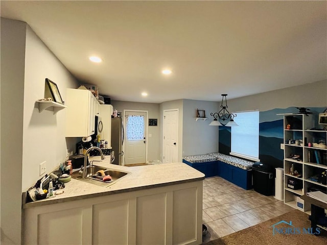 kitchen with white cabinetry, sink, hanging light fixtures, blue cabinets, and stainless steel fridge