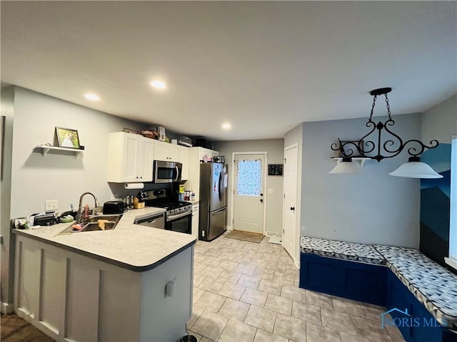 kitchen with sink, kitchen peninsula, hanging light fixtures, white cabinetry, and stainless steel appliances