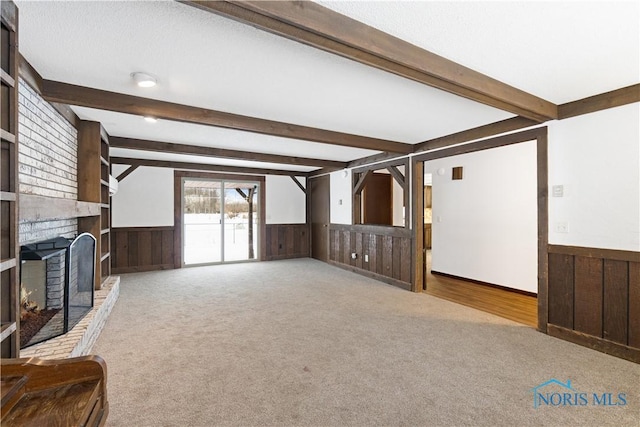 carpeted living room featuring beam ceiling and a fireplace