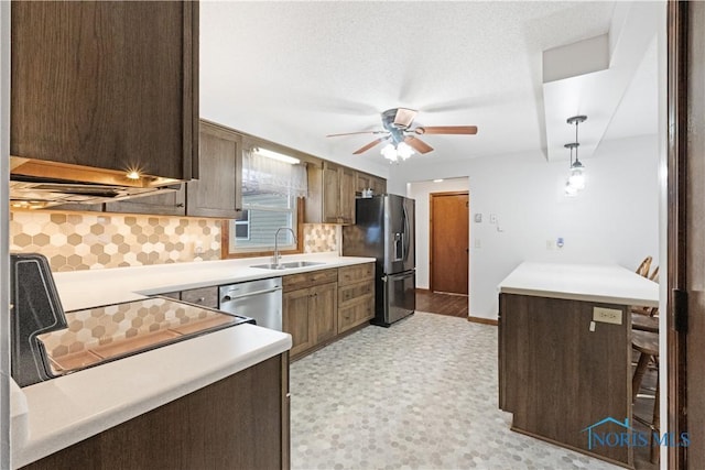 kitchen with sink, hanging light fixtures, a kitchen breakfast bar, decorative backsplash, and appliances with stainless steel finishes