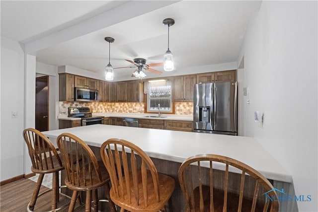 kitchen featuring backsplash, kitchen peninsula, sink, and appliances with stainless steel finishes