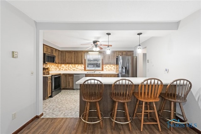 kitchen with tasteful backsplash, stainless steel appliances, sink, pendant lighting, and light hardwood / wood-style flooring