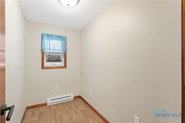 unfurnished room featuring light wood-type flooring and a baseboard heating unit