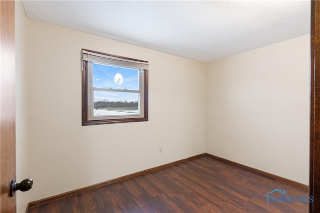 spare room featuring dark hardwood / wood-style flooring and a textured ceiling