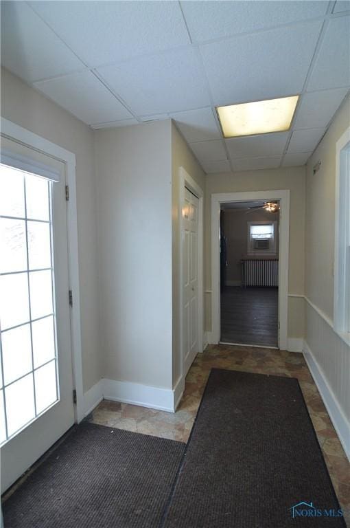 hallway with radiator heating unit and a paneled ceiling