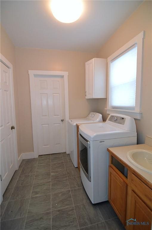 laundry area with washing machine and dryer, cabinets, and sink