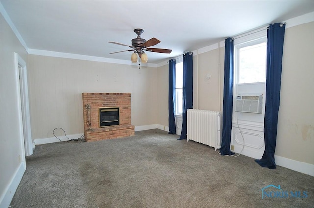 unfurnished living room with radiator, ceiling fan, ornamental molding, carpet flooring, and a brick fireplace